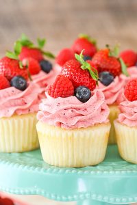 Berries and Cream Cupcakes - mixed berry buttercream paired with a moist vanilla cupcake stuffed with whipped cream cheese filling, topped with fresh strawberries, raspberries and blueberries | by Lindsay Conchar for TheCakeBlog.com