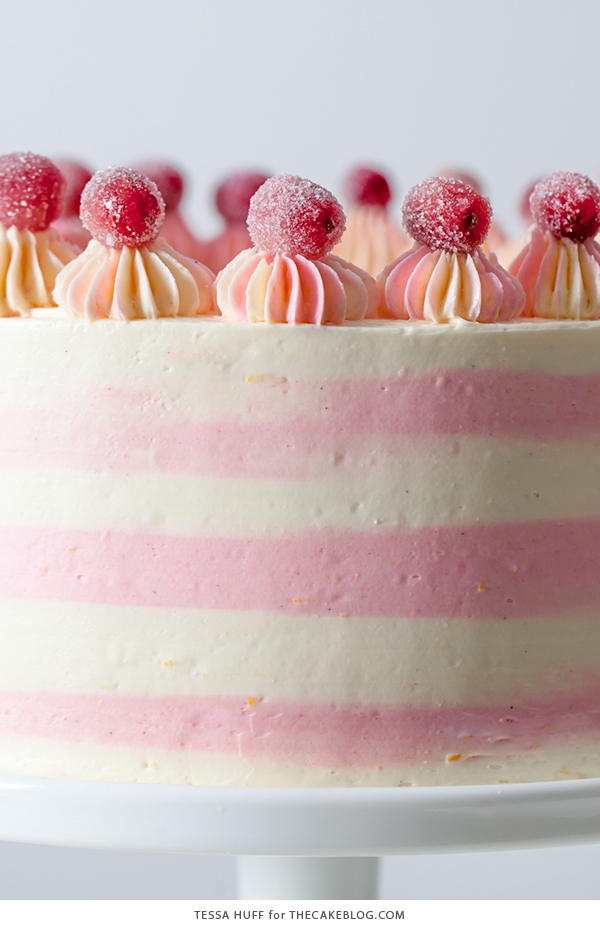 Cranberry Orange Spice Cake - orange cake studded with cranberries topped with white chocolate orange frosting in festive pink and white buttercream stripes | by Tessa Huff for TheCakeBlog.com