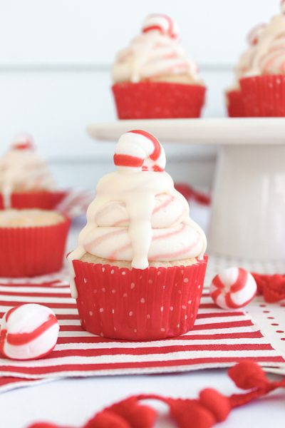 White Chocolate Peppermint Cupcakes - delicious white cake speckled with candy canes, topped with red and white swirled buttercream and white chocolate ganache | by ellenJAY for TheCakeBlog.com