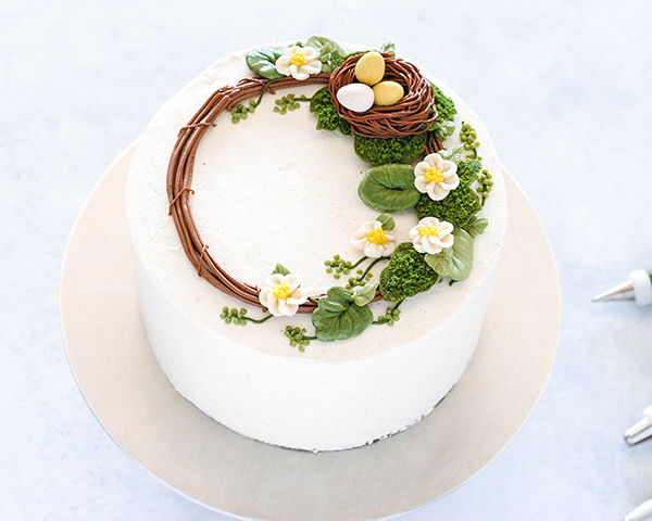Spring Wreath Cake - how to make a buttercream wreath cake a bird's nest, cherry blossoms, green berries and cookie moss | by Carrie Sellman for TheCakeBlog.com #easter #easterdinnerideas #mothersday #cake